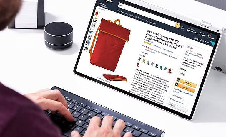 A person typing on a laptop with its screen showing an Amazon product listing