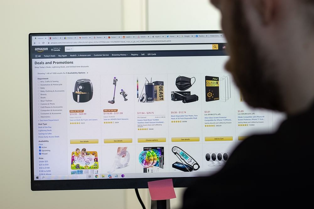 A man browsing Amazon’s Deals and Promotions page on his computer