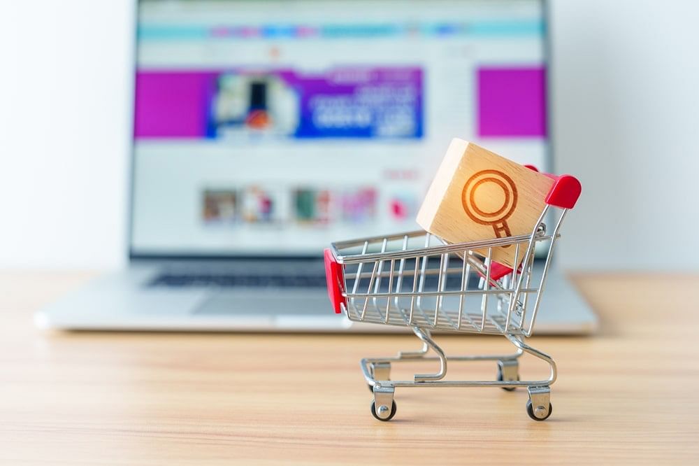 Shopping cart with magnifying icon block and laptop computer
