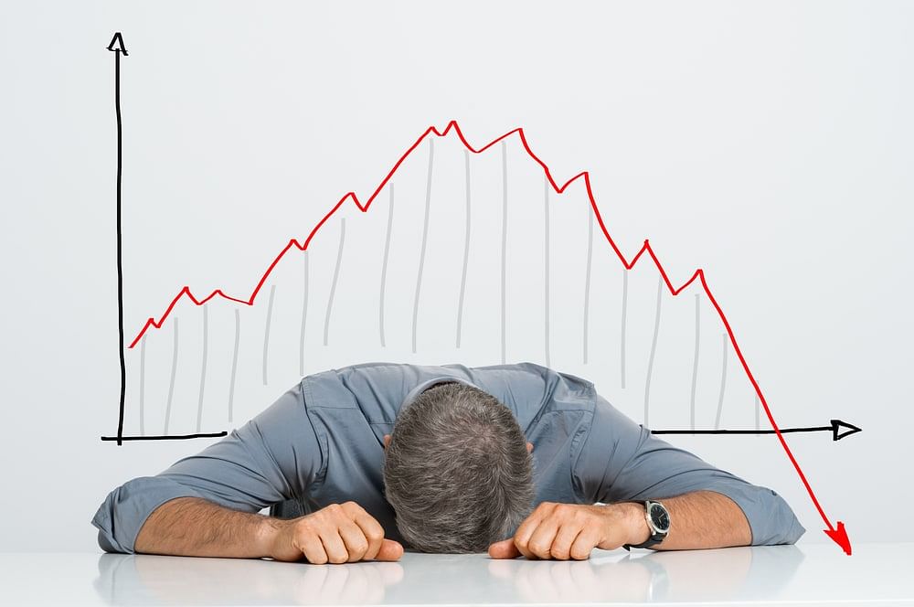 Depressed businessman leaning his head below a bad market revenue chart