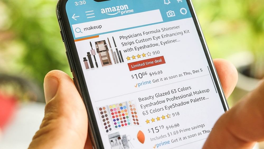Amazon search results for “makeup” shown on a mobile screen, held by a person