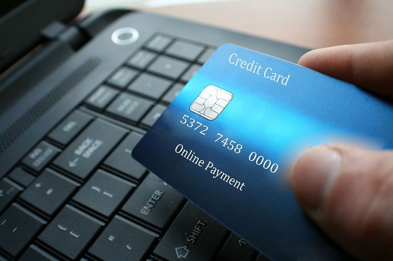 a man holding a credit card with a laptop keyboard on the background