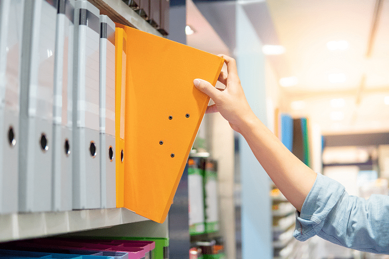 Woman getting a yellow binder from a shelf