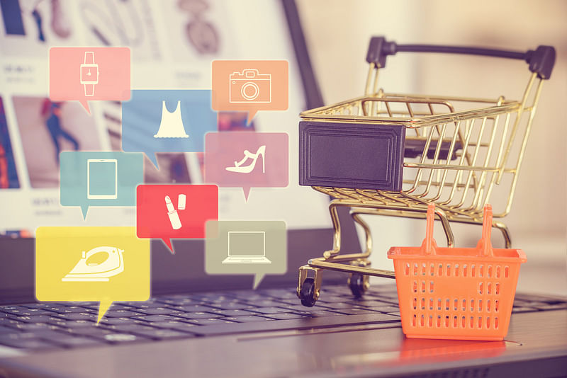 On the left side: different icons of items inside a box. On the right: a shopping cart and a basket on top of an open laptop.