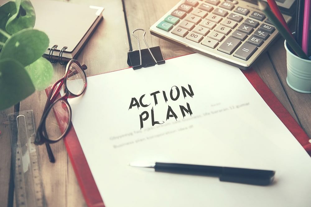 The word ACTION PLAN written on office paper lying on top of a wooden desk