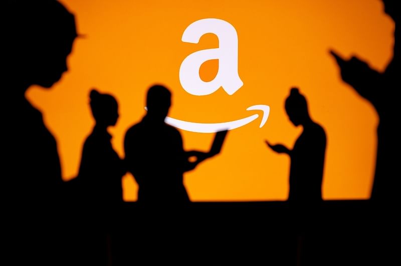 silhouettes of people on their phones with orange amazon logo in the background