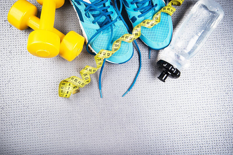 Top shot, upper portion: Yellow dumbells, sky blue training shoes, yellow tape measure, and a drinking container with a black cover. 