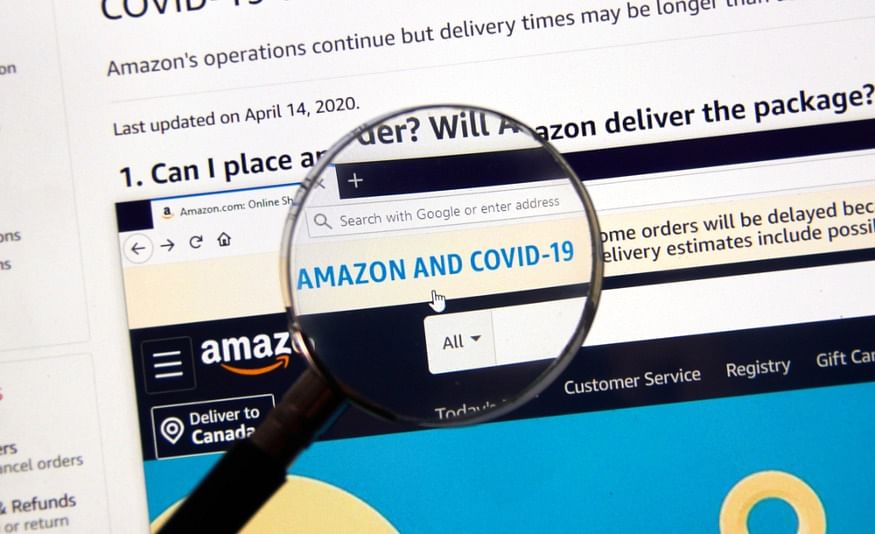 shot of a person holding a magnifying glass over a computer screen highlighting the words “Amazon and covid-19”