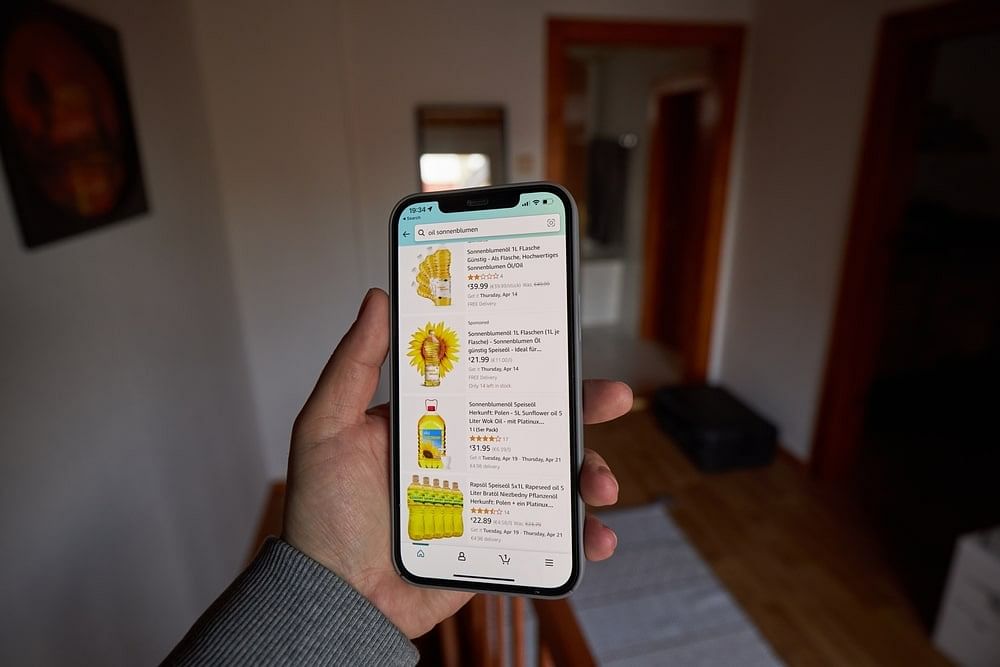 A man looking at sunflower oil listings on Amazon on his smartphone
