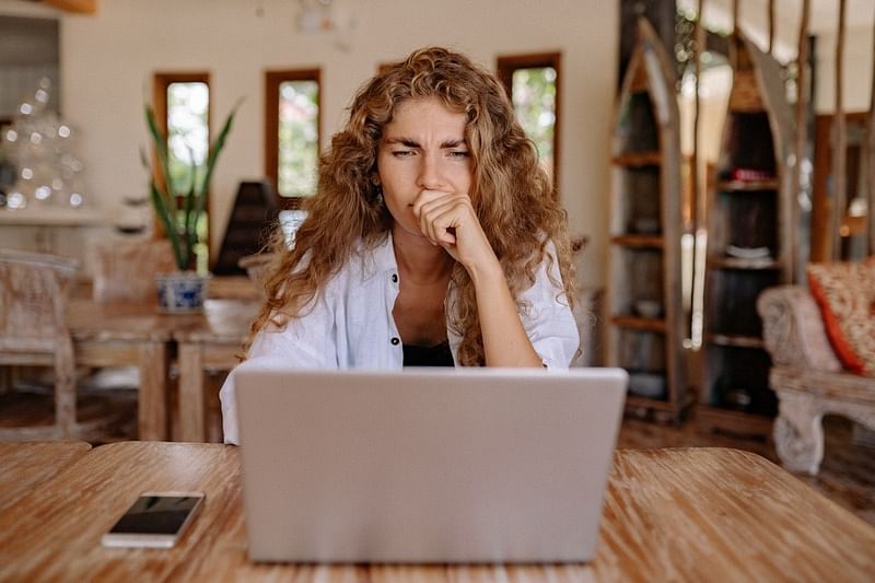 a woman sitting while looking seriously in front of her laptop