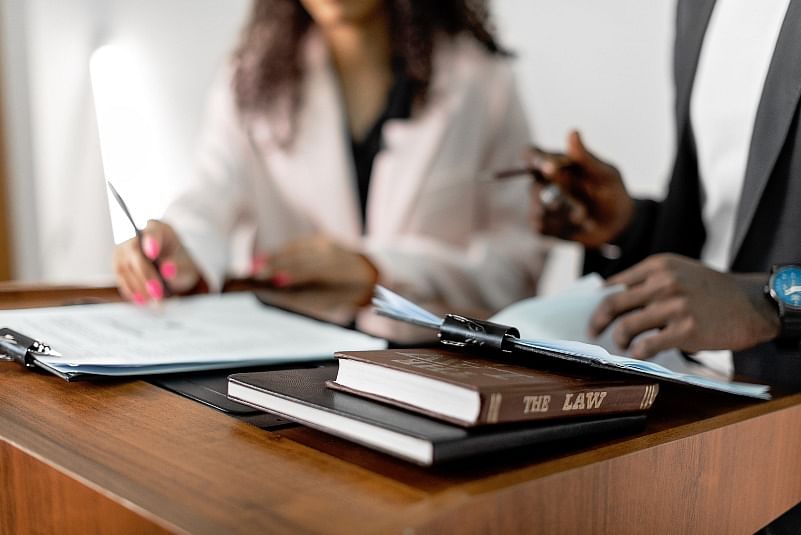 closeup shot focusing on law books and papers with two lawyers discussing in the background