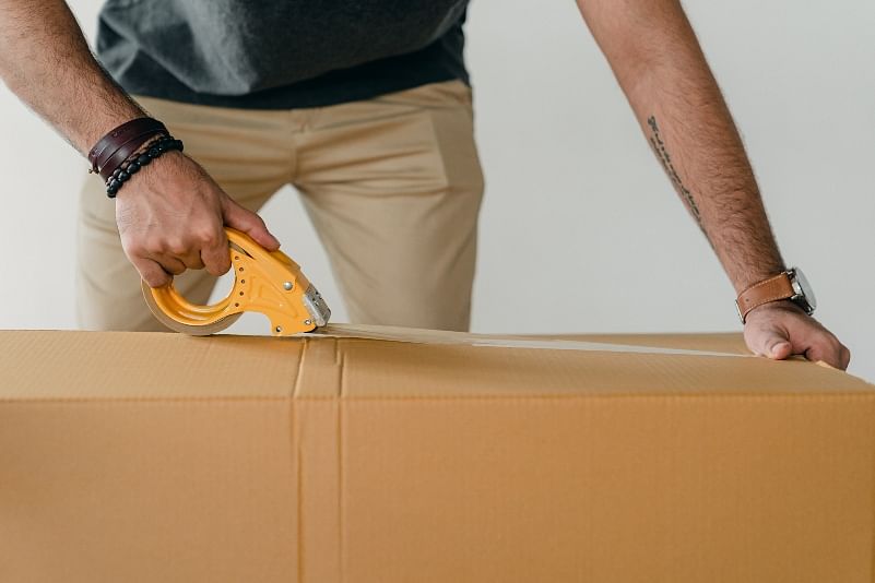 closeup shot of a person sealing a package box with packaging tape
