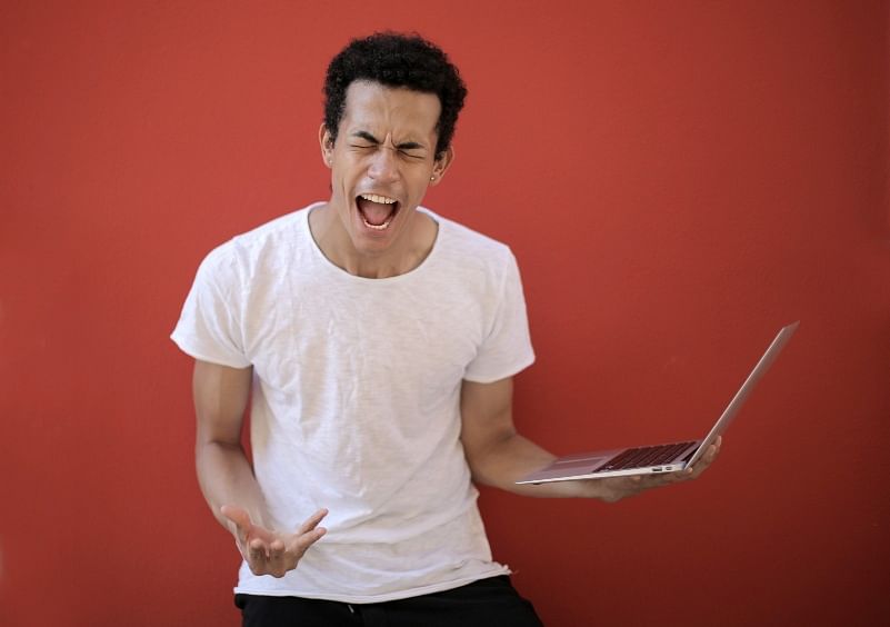 shot of a man shouting while holding his laptop against a red background