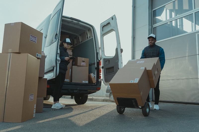 shot of delivery persons unloading packages from their delivery van